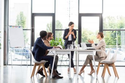 multiethnic businesspeople sitting at tables during conference in office